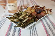 there is a white plate with some vegetables on it and a bottle of wine in the background