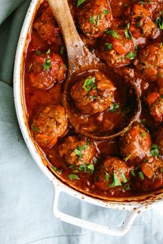 meatballs and gravy in a pot with a wooden spoon