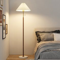 a bedroom with a bed, lamp and pictures on the wall