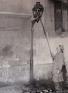 an old black and white photo of a person spraying water on a street lamp