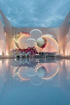 an indoor wedding setup with flowers and candles on the water's edge at dusk