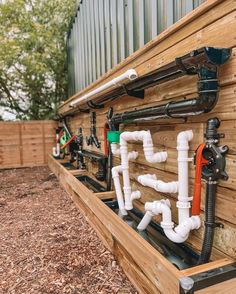 pipes are lined up on the side of a wooden structure in front of a fence