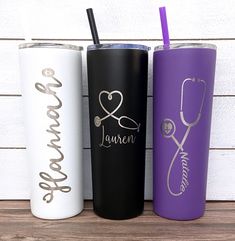 three personalized tumblers are lined up next to each other on a wooden surface