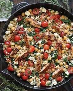 a skillet filled with chicken, tomatoes and chickpeas