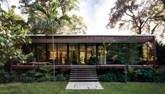 the house is surrounded by greenery and trees, with stairs leading up to it