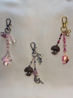 four different keychains with charms attached to them on a white cloth covered surface