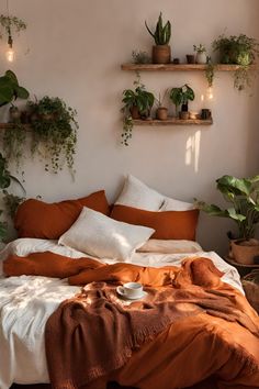 a bed with lots of plants on the wall above it and an orange comforter