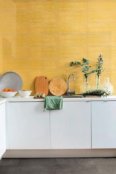 a kitchen with yellow walls and white cabinets is pictured in this image, there are dishes on the counter