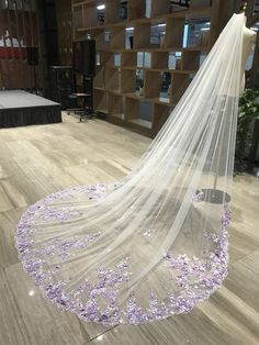 a wedding veil with purple flowers on the floor