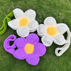 three crocheted flowers are laying on the grass