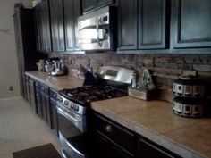 a kitchen with black cabinets and stainless steel stove top oven in the middle of it