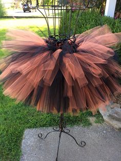 a brown and black tutule on a metal stand in the grass near some bushes