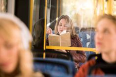 a woman sitting on a bus reading a book