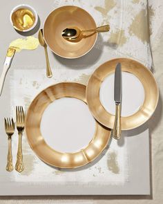 a place setting with gold colored plates and silverware