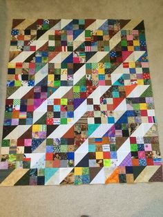 a very large colorful patchwork quilt hanging on the wall next to a pair of scissors