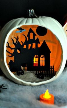 a paper cut out of a house on top of a pumpkin