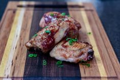 two pieces of meat sitting on top of a wooden cutting board