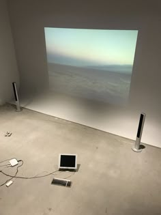 an empty room with two speakers and a laptop on the floor