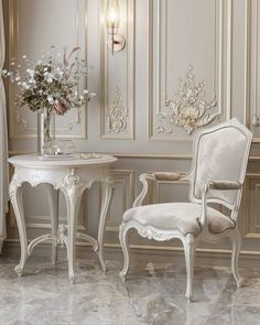 two white chairs and a table in a room with gold trimmings on the walls