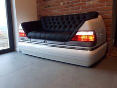 a black and white couch sitting on the back of a car in front of a brick wall