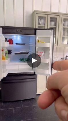 a person is holding an open refrigerator door