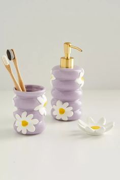 two purple and white flowered toothbrush holders next to each other