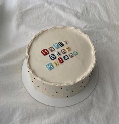 a birthday cake with letters on it sitting on a white tablecloth covered table cloth