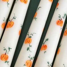 four white candles with orange pumpkins on them are lined up in a row and ready to be decorated