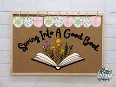 an open book sitting on top of a bulletin board that says spring into a good book