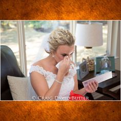 a woman in a wedding dress is holding her hand to her nose and looking at the paper