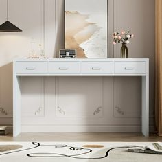 a white table with two drawers and a phone on it in front of a painting