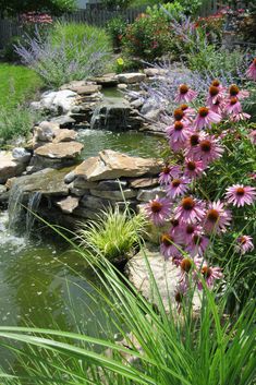 a garden with flowers, rocks and water features in the foreground as well as a pond