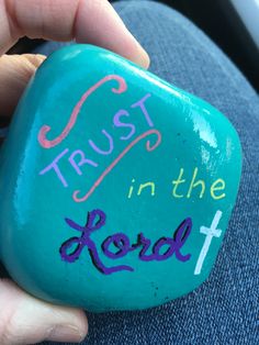 a hand holding a rock with the words trust in the lord written on it