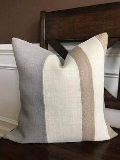 a white and grey striped pillow sitting on top of a wooden chair next to a wall