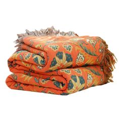 two blankets folded on top of each other in an orange and blue floral pattern with fringes