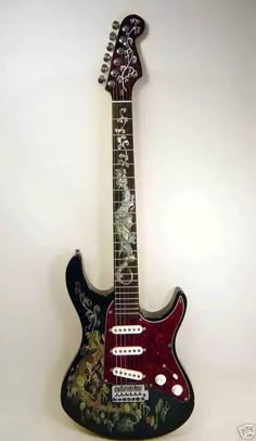 a black and red guitar sitting on top of a white wall