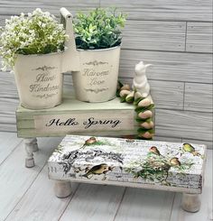 three white planters sitting next to each other on top of a wooden bench and table