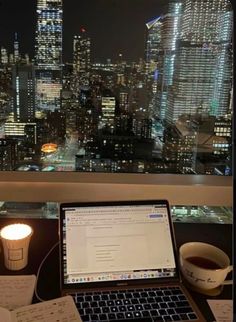 an open laptop computer sitting on top of a desk next to a cup of coffee