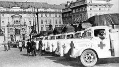 black and white photograph of people standing in front of trucks with medical equipment on the back