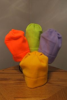 four different colored hats sitting on top of a wooden table