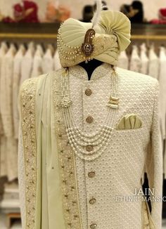 a white suit with pearls on the neck and collar, standing in front of some dresses