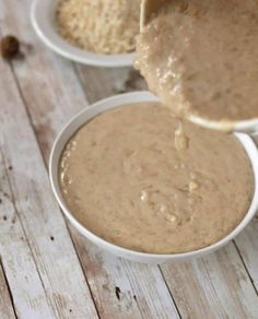 two white bowls filled with peanut butter on top of a wooden table