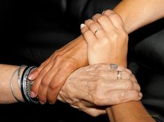 two women and one man holding each other's hands while they are wearing bracelets