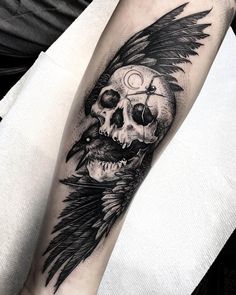 a man's arm with a skull and wings tattoo on it