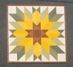 a yellow and green star quilt hanging on the side of a building