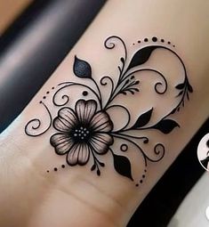 a black and white flower tattoo design on the wrist or leg, with swirls and leaves