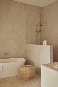 a white bath tub sitting next to a walk in shower and a wooden basket on the floor