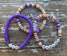 two purple and yellow bracelets sitting on top of a wooden table