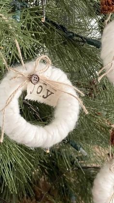 yarn wreath ornament hanging from a christmas tree with the word joy on it