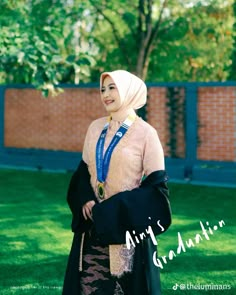 a woman wearing a hijab standing in the grass with her hand on her hip